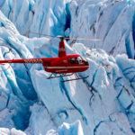 Alpine Air helicopter in flight with blue glacier background